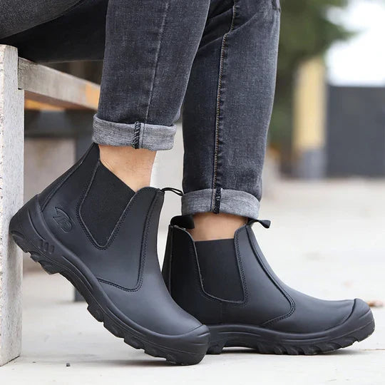 Model in rolled grey jeans sitting on a concrete bench wearing black leather pull-on boots outdoors 8