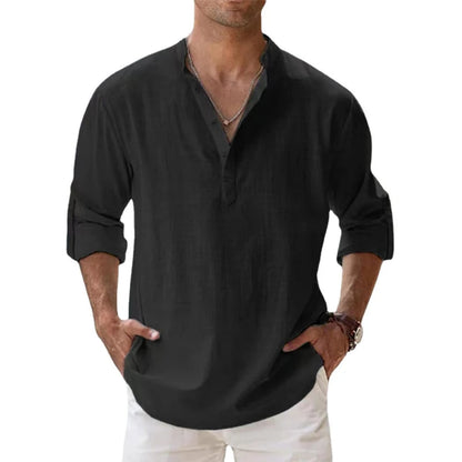 Man wearing the Henley shirt in black, with a short button placket, rolled sleeves and hands in white trouser pockets. 7