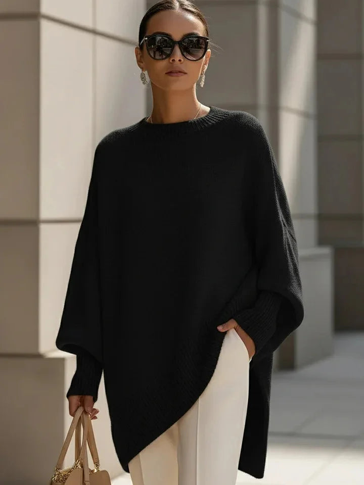 Black jumper worn with sunglasses, drop earrings, white trousers and a beige handbag against stone columns 8