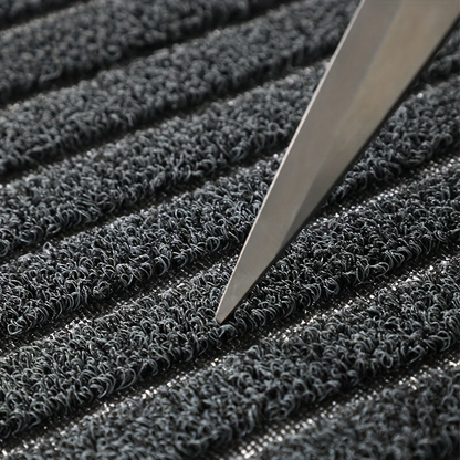 Close-up of the curly grey loops of the pile, with the point of a blade resting between two stripes. 5