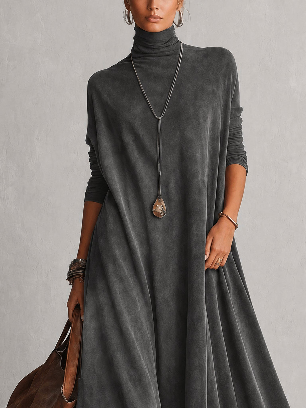 Close-up of the charcoal grey dress's turtleneck and draped long-sleeved bodice with a pendant necklace 17