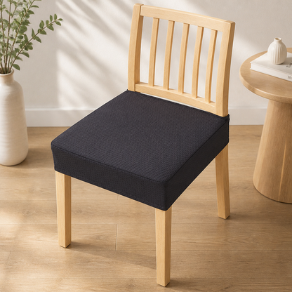 Black textured seat cover on a light wooden slatted chair, with a round side table and vase beside it. 10