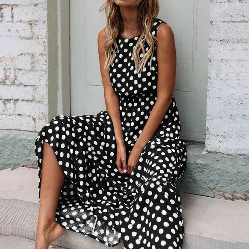 Woman sitting on a stone step wearing the black polka dot dress, showing the sleeveless bodice and full, tiered skirt. 4