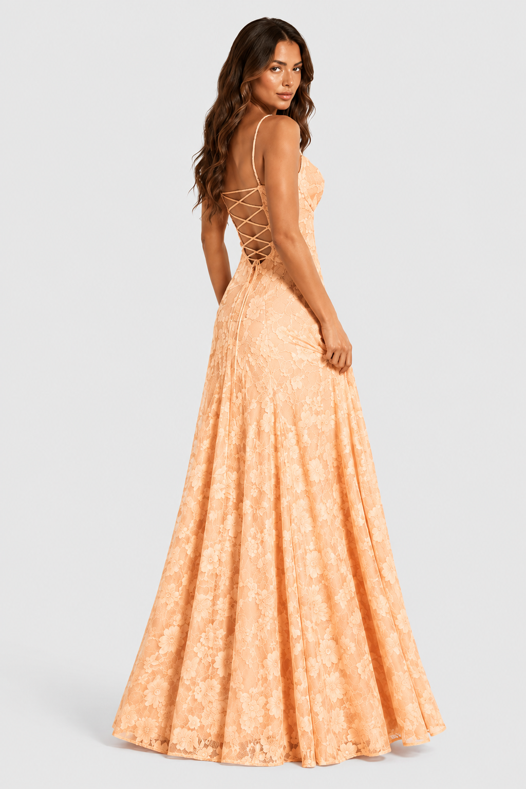 Back view of a peach floral lace gown with criss-cross lace-up back, model glancing over her shoulder. 14