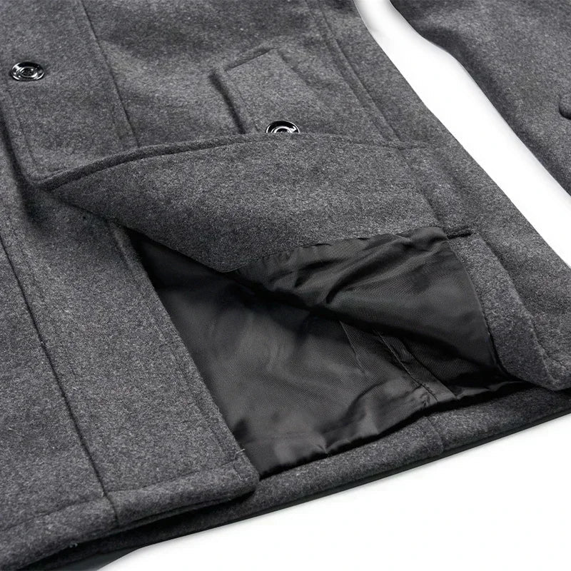 Close-up of the grey coat's lower front, with a pocket flap lifted to reveal the black lining 9