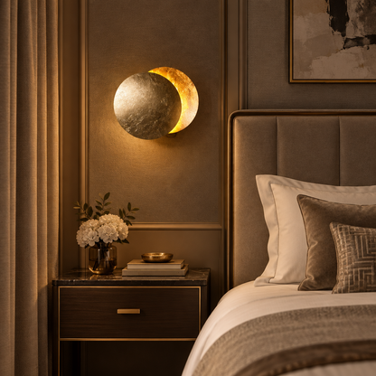 Gold-leaf moon wall lamp glowing above a bedside table in a warm, upholstered bedroom 1