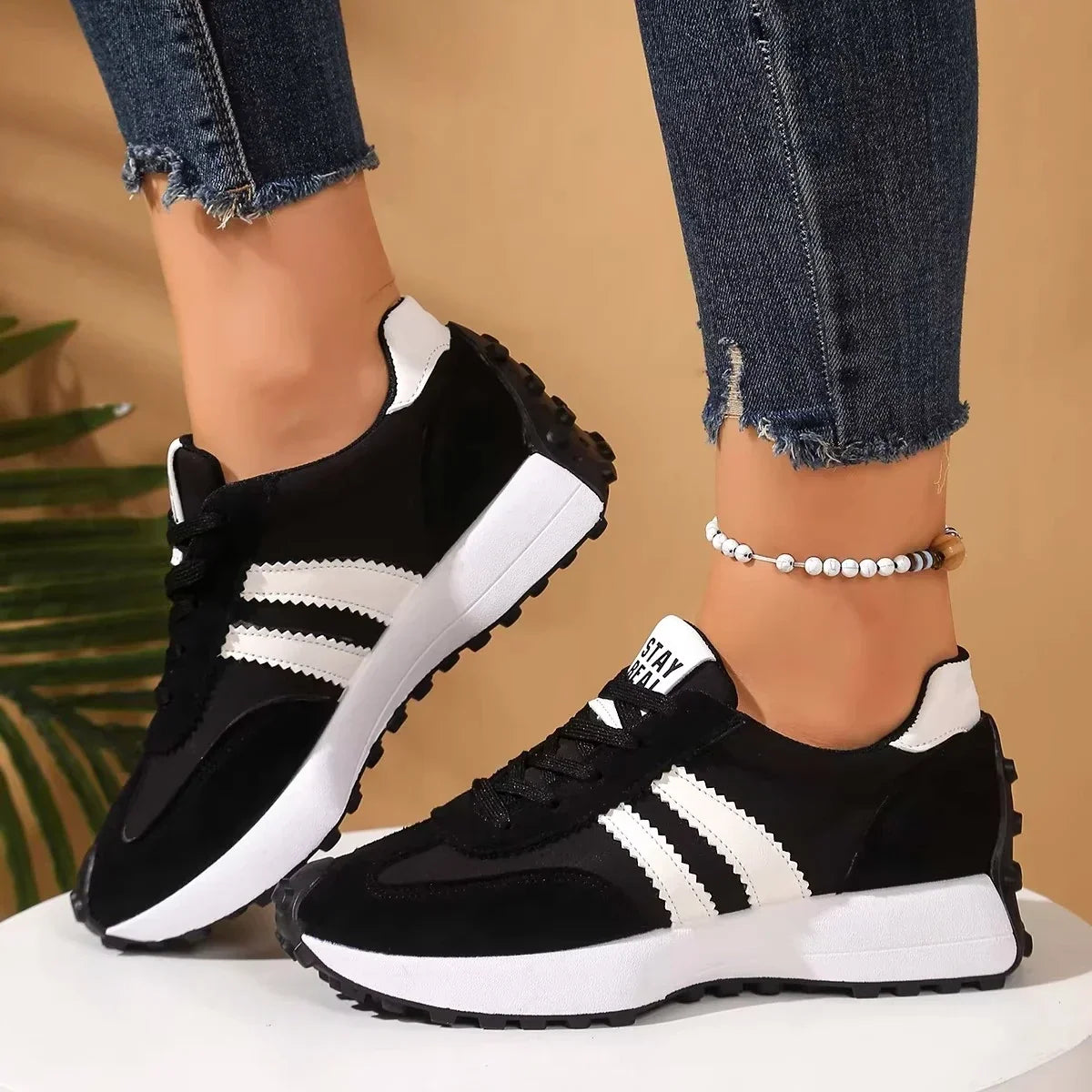 Black trainers with white stripes and platform soles worn with dark jeans, side view on a white plinth 9