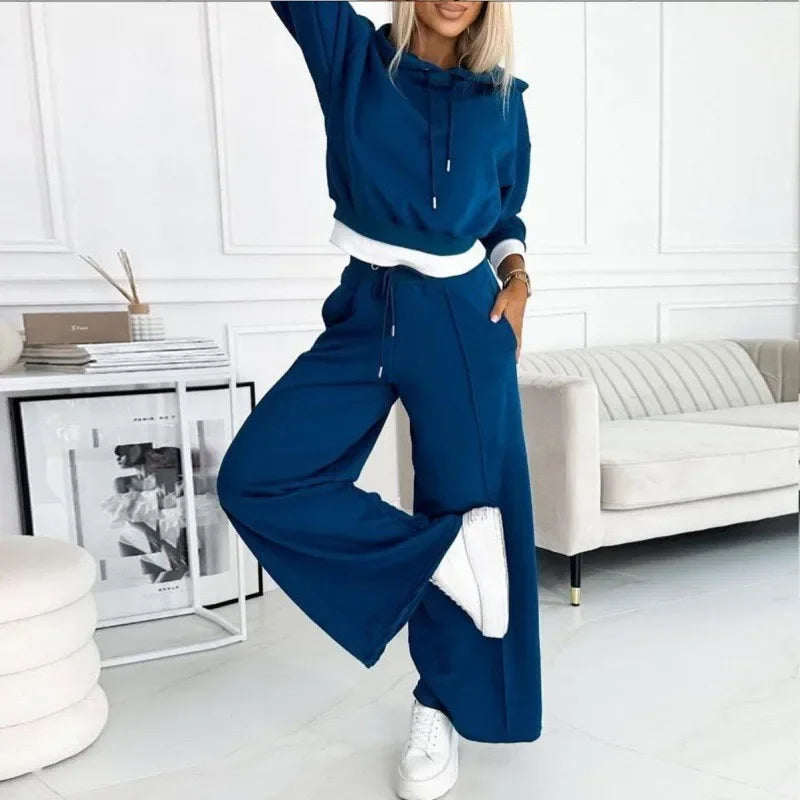 Blue hooded set with white hem trim, model balancing on one leg in a bright lounge 9