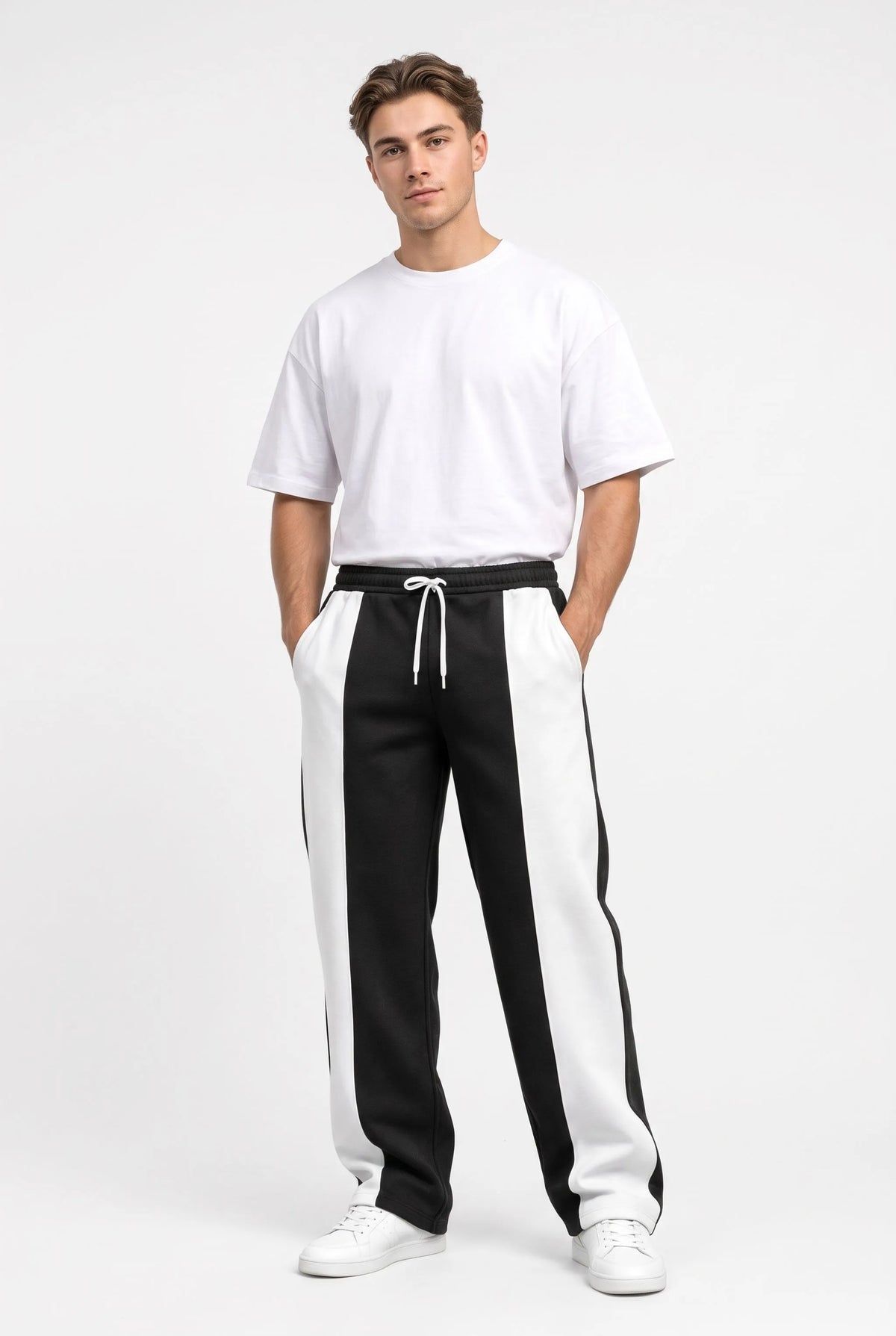 Studio full-length shot of a model in black sweatpants with white panels and oversized white tee 9