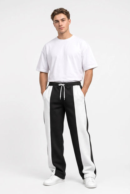 Studio full-length shot of a model in black sweatpants with white panels and oversized white tee 9