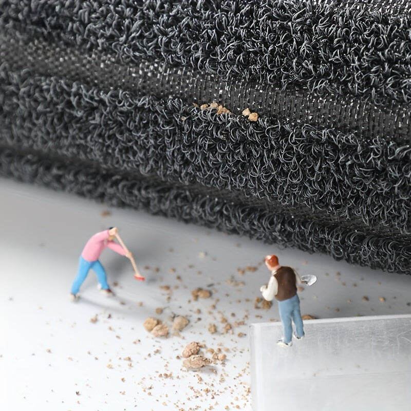 Rolled edge of the mat showing the loop pile and woven backing, with tiny figures sweeping dirt on the floor below. 6