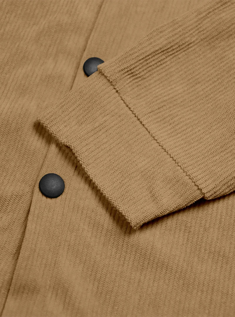 Close-up of the tan shirt's ribbed cuff and black snap buttons on the front placket 9