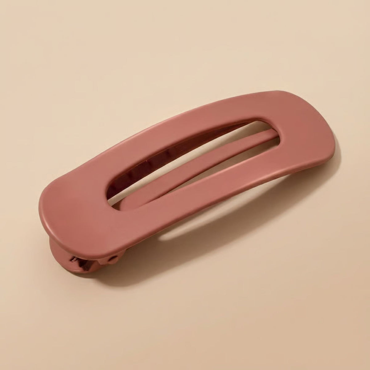 Matte terracotta-pink slim flat clip seen at an angle, showing the hinge and teeth underneath 9