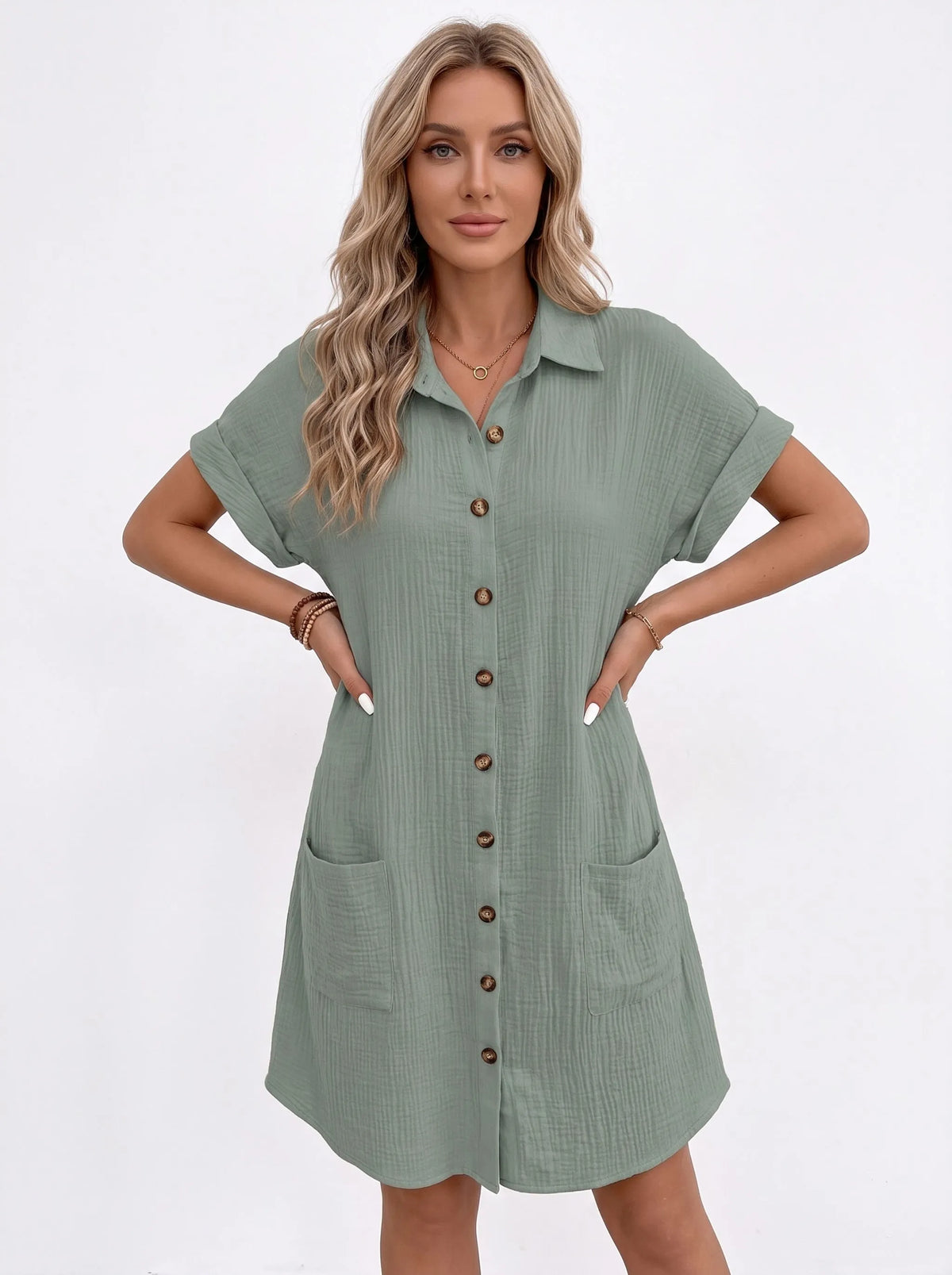Sage green shirt dress on a model with both hands on hips, showing two front pockets 9