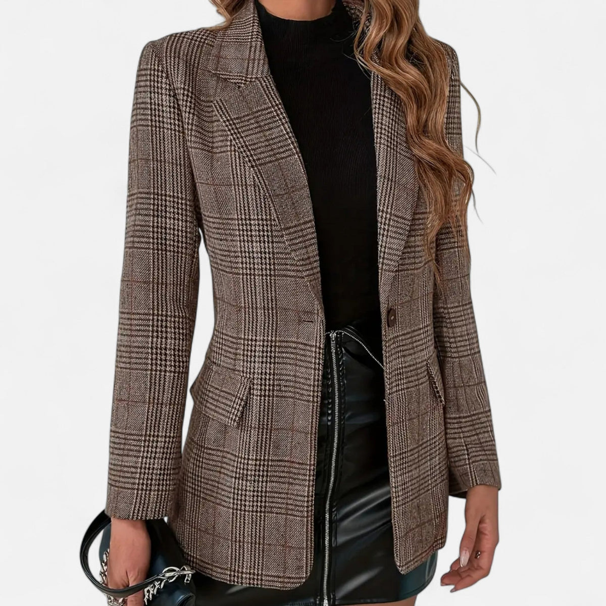 Close-up front view of the brown check blazer worn open over a black top and black leather skirt, showing lapels, button and flap pockets. 1