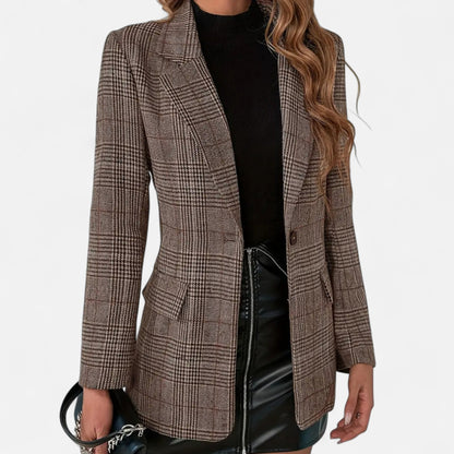 Close-up front view of the brown check blazer worn open over a black top and black leather skirt, showing lapels, button and flap pockets. 1