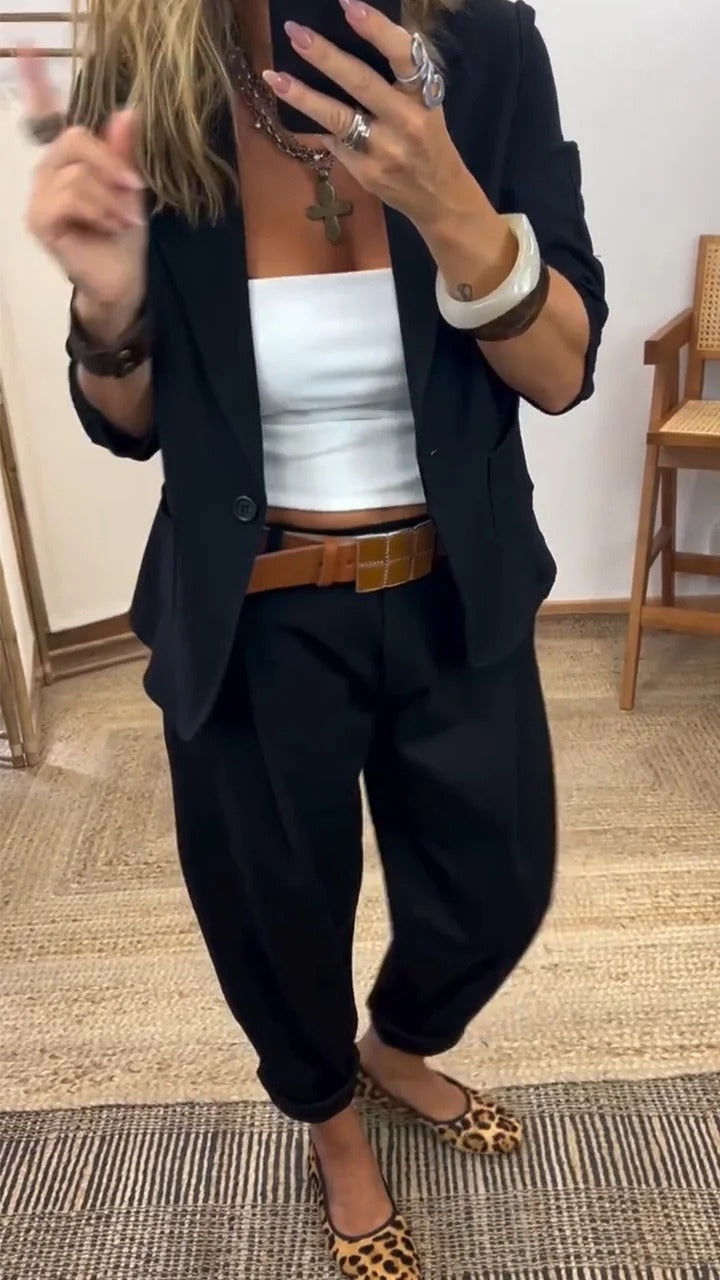 Woman wearing the black single-button blazer and loose black trousers with a tan belt and leopard-print flats, shown in a mirror selfie. 3