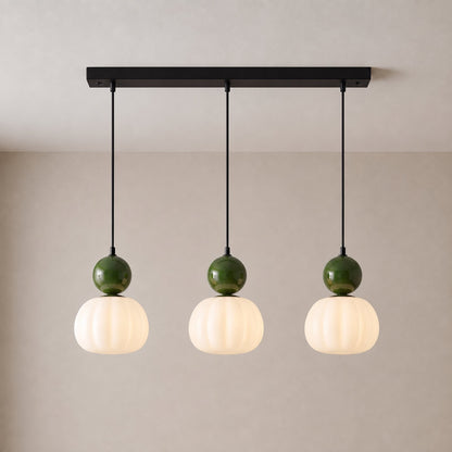 Three-head pendant with deep green caps and glowing fluted shades on a black ceiling bar 10