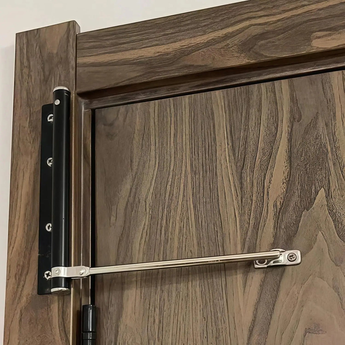 Black-bodied closer with silver arm fitted to a dark walnut-effect door, seen close up 3