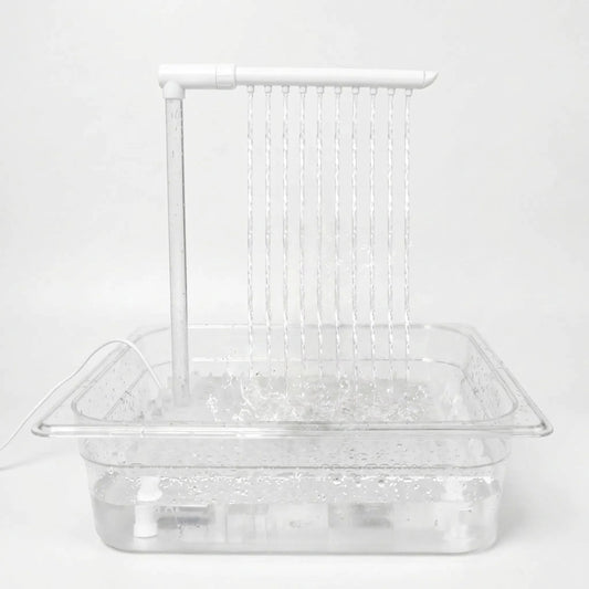 Clear tray with a pump and overhead pipe running, ten thin streams of water falling into the filled basin against a plain background. 1