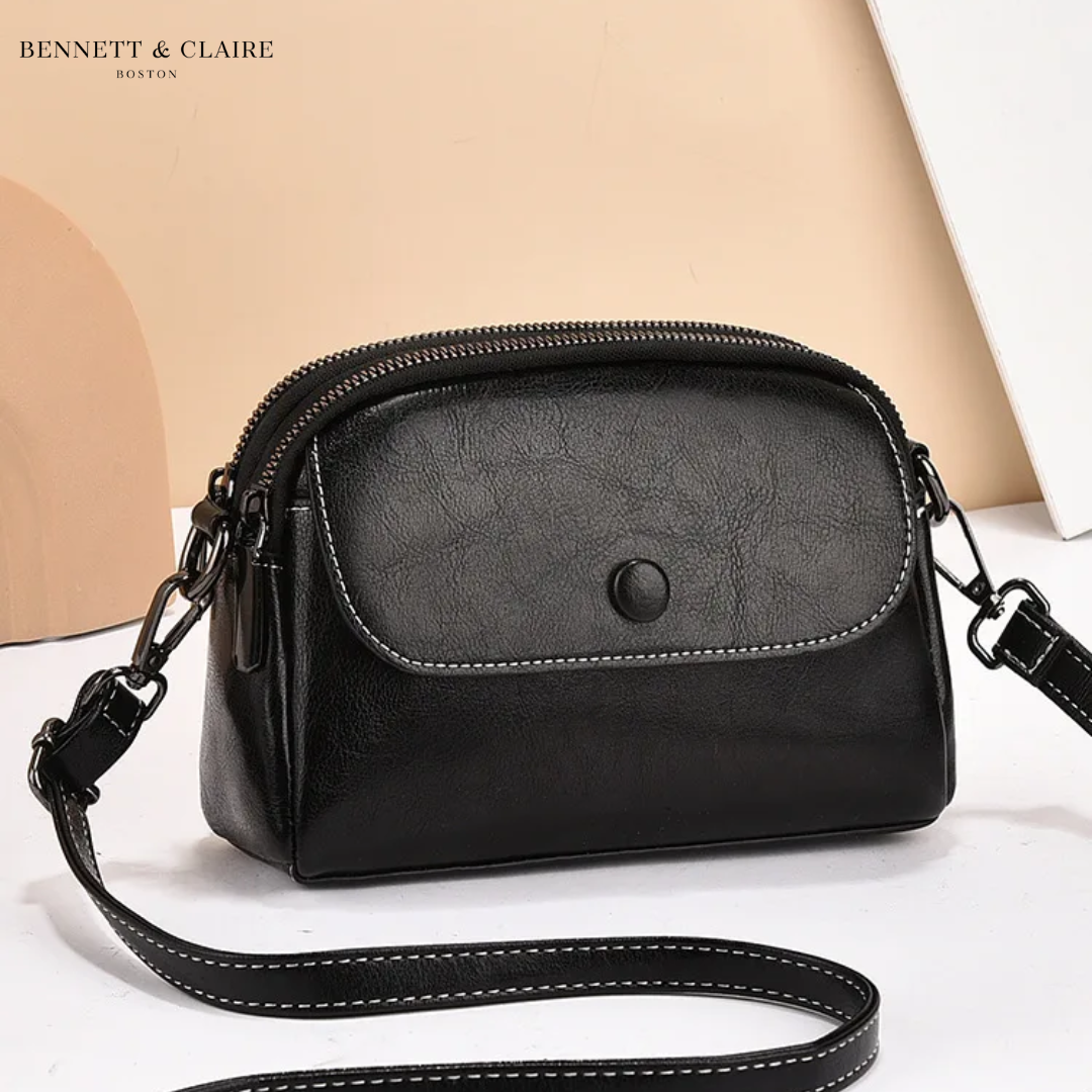 Black version of the crossbody bag with a stitched front flap, studded closure, double zip top and long matching strap. 2