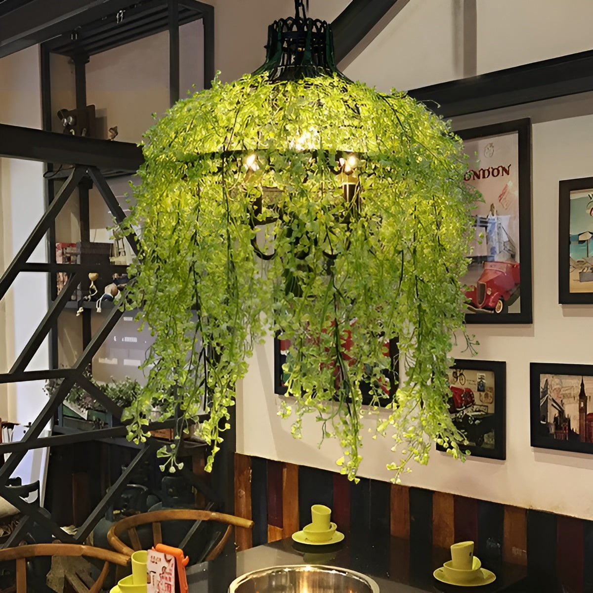Chandelier draped in yellow-green leafy vines above a dining table, with framed travel posters on the wall 6