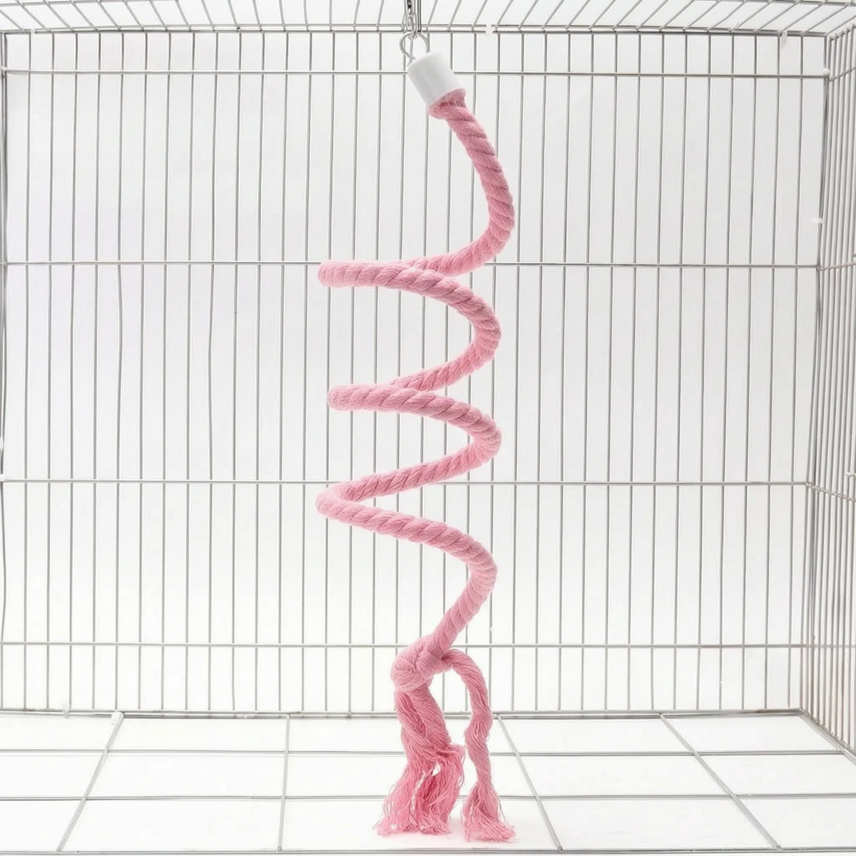Pink version of the spiral rope perch hanging from a small hook in a white wire cage, with a knotted, frayed end. 6