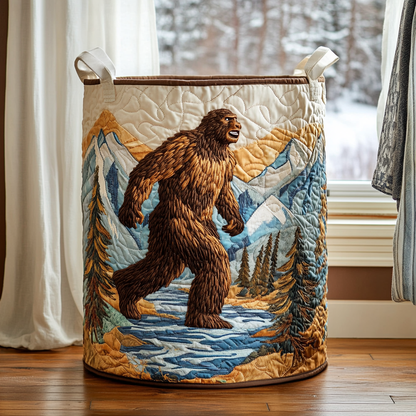 Quilted basket with an embroidered bigfoot walking through a river valley of snowy mountains and pine trees, with brown trim. 7