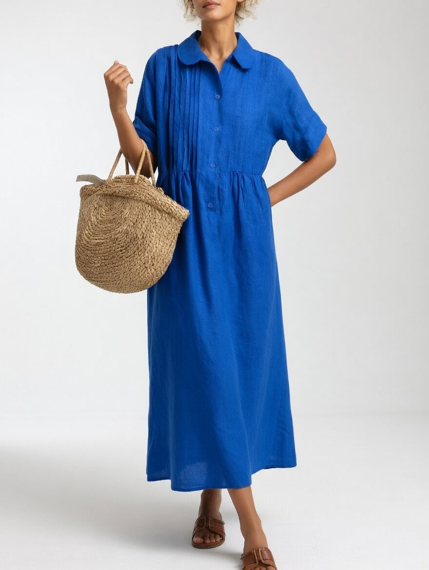 Model in the bright cobalt blue dress with one hand on hip, showing pintucks, gathered waist and rolled short sleeves. 3