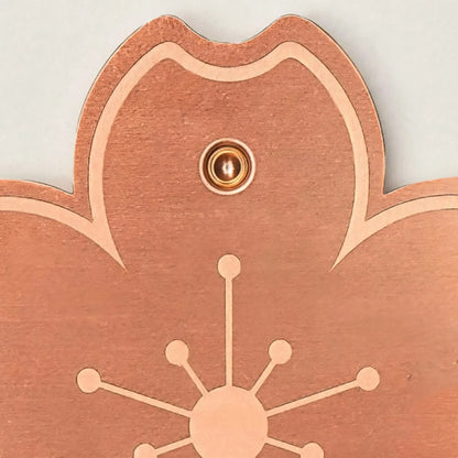 Close-up of one petal of the copper-coloured disc, showing the brushed metal surface, engraved outline and the small round stud. 3
