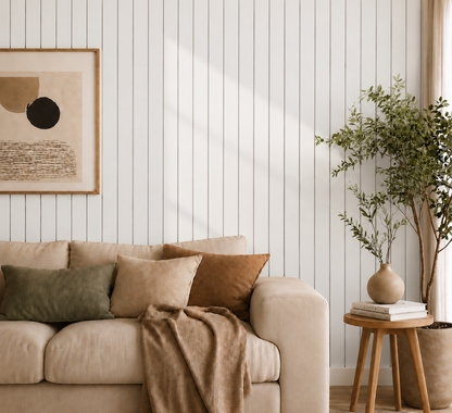 Off-white slat wall behind a cream sofa with cushions, framed print, plant and stool 20