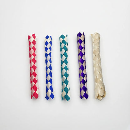 Five woven finger traps lined up side by side on white, in red, blue, teal, purple and plain natural straw. 1