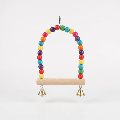 Front view of the bird swing on a plain white background, with a natural wooden perch, colourful bead arch and two brass bells. 1