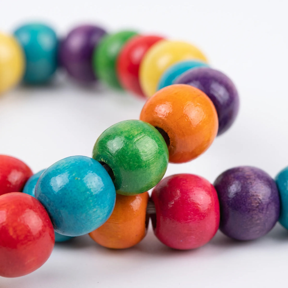 Close-up of the glossy painted wooden beads in red, blue, green, orange, pink and purple threaded along the arch. 4