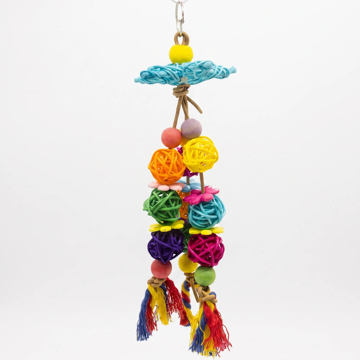 Full front view of the hanging toy against white, with woven rattan balls, wooden beads, flower shapes and cotton tassels. 1