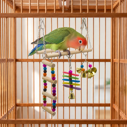 Green lovebird with a red face perched on the swing inside a wooden cage, ladder, slats and bells hanging below. 2