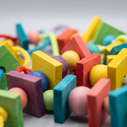 Close-up detail of the dyed wooden blocks and round beads threaded together with braided cotton rope. 4