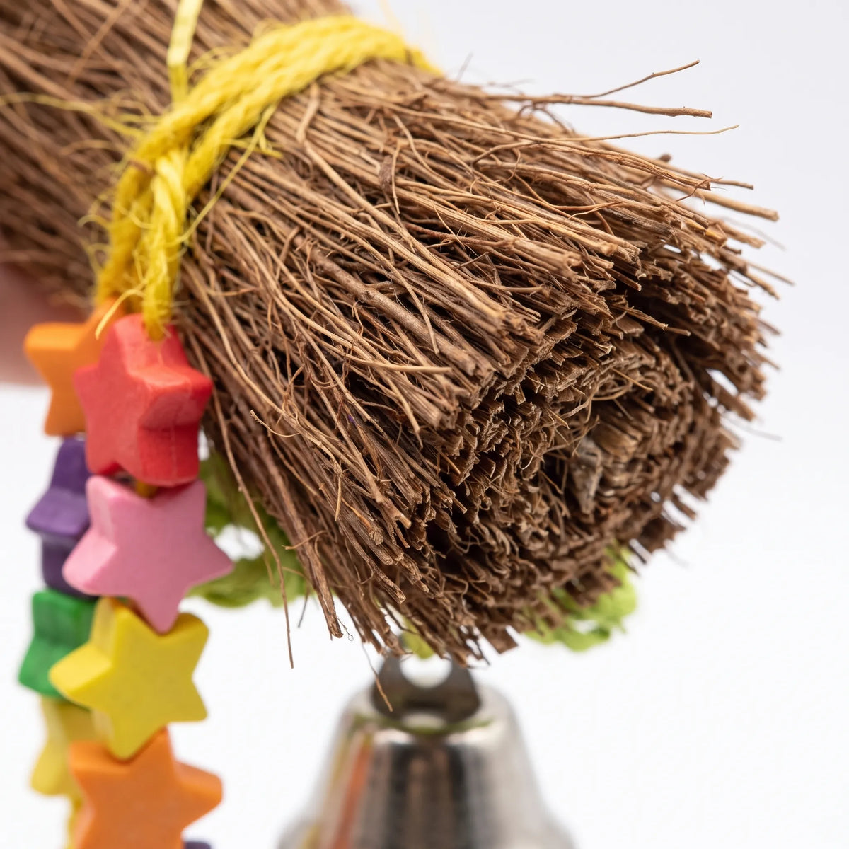 Close-up of the frayed brown fibre bundle, yellow twine, colourful wooden star beads and silver bell. 2