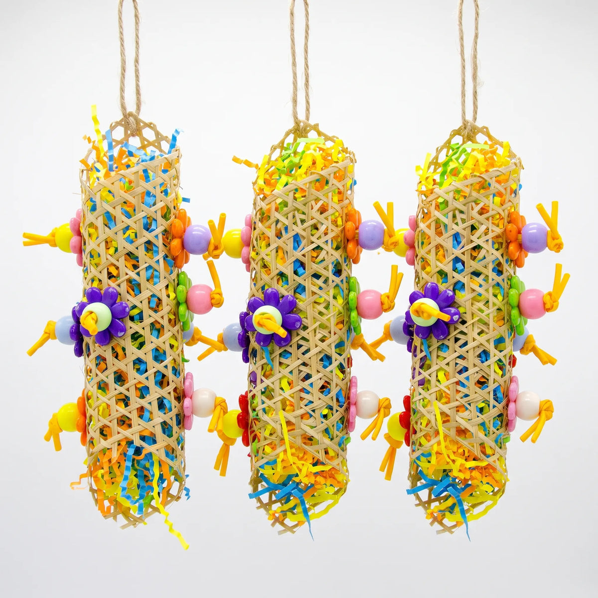 Three woven cane tubes stuffed with shredded coloured paper, with flower-shaped and round beads, hanging from jute loops. 3