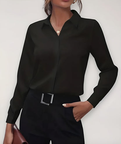 Black blouse worn by a model with black trousers, a square buckle belt and a brown bag 1