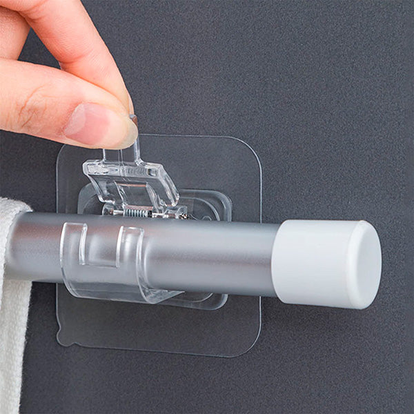 Close-up of a finger lifting the spring clip on a clear adhesive holder gripping a rod with a towel. 2