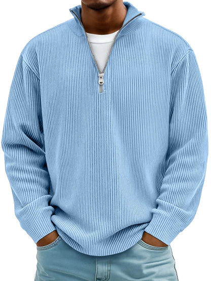 Man wearing the half-zip ribbed jumper in light blue over a white tee, hands in jeans pockets 1