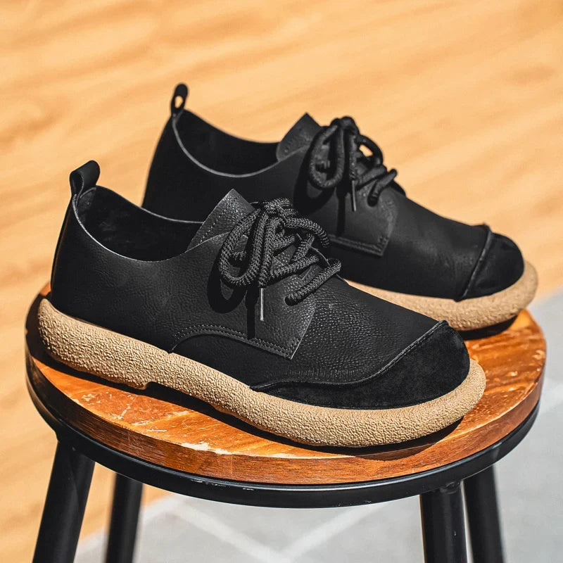 Black lace-up shoes with tan soles displayed on a round wooden stool 11