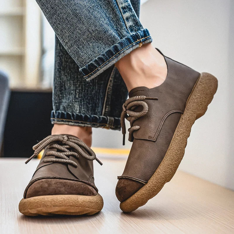 Brown lace-up shoes worn mid-stride with rolled blue jeans, showing the suede toe caps 15