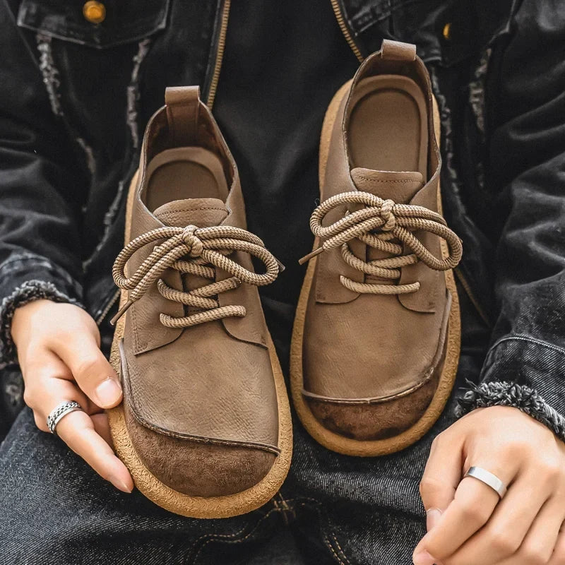 Tan lace-up shoes held toes down against a denim jacket, showing laces, tongues and insoles 2