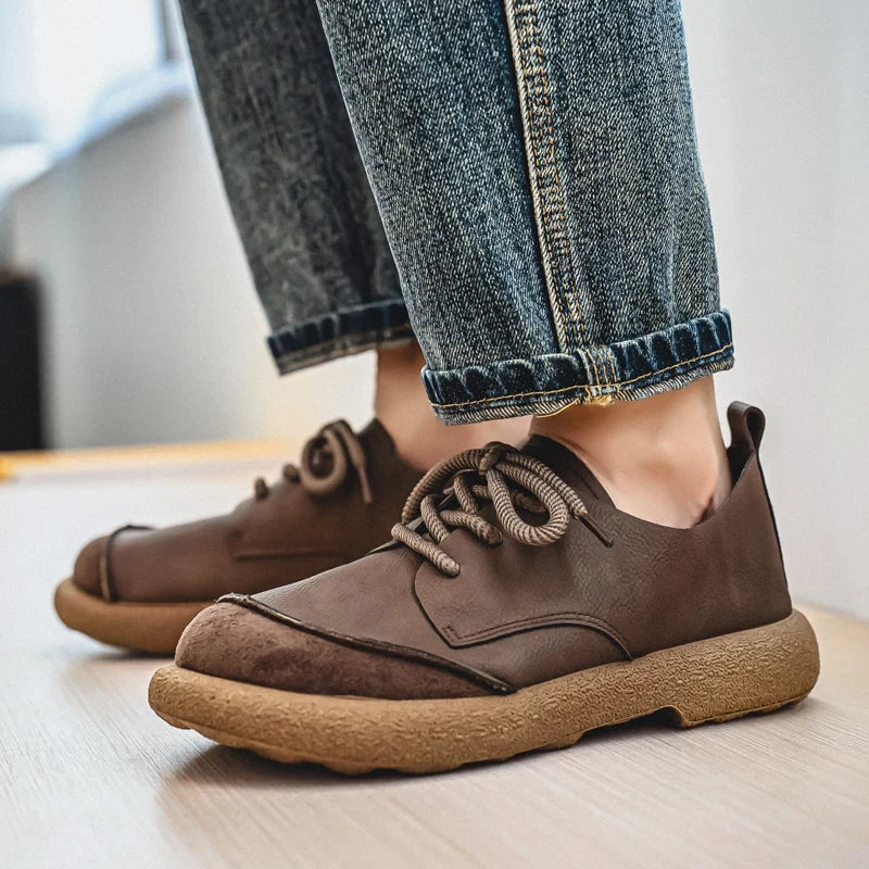 Side view of brown lace-up shoes worn with rolled-up blue jeans, showing the suede toe cap 4