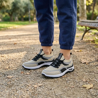 Woman wearing beige, grey and black mesh trainers with navy joggers, standing on a gravel park path. 38