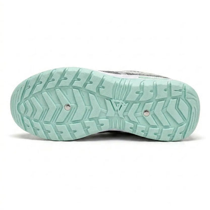 Underside of the mint green trainer showing the deep, patterned tread of the rubber outsole with two small metal studs. 18