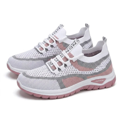 Pair of white, grey and pink mesh trainers with elasticated laces and a pink sole, seen at an angle. 25