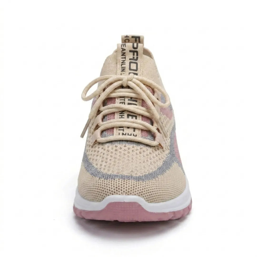 Front view of a beige mesh trainer with pink and grey panels, showing the laces and rounded toe. 35